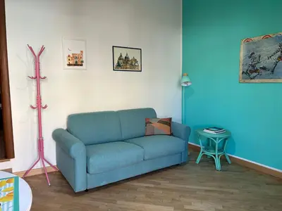 a living room with a blue couch and a lamp at Glicine House in Palermo