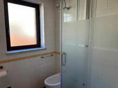 a bathroom with a shower and a toilet and a window at Glicine House in Palermo