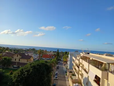 a city street with buildings and the ocean in the background at HolidayHouse Belvedere in Terrasini
