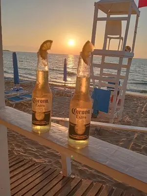 two bottles of beer sitting on a table on the beach at Perla del Mare in Trappeto