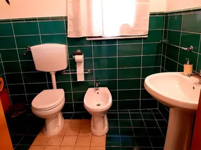 a green tiled bathroom with a toilet and a sink at Ballarò room in Palermo