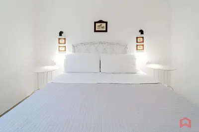 a white bed with white pillows and two tables at Grande e Luminosa Villa con Piscina vicino al Mare in Terrasini