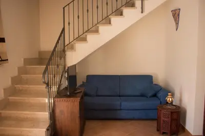 a blue couch in a living room with stairs at Oasi del Sole - sun and sea -Casa Colombo in San Vito lo Capo