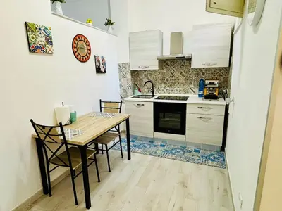 a small kitchen with a wooden table and chairs at MaxMondello in Palermo