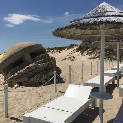 a beach with benches and an umbrella on the sand at Suite Vicino al Mare in Carini