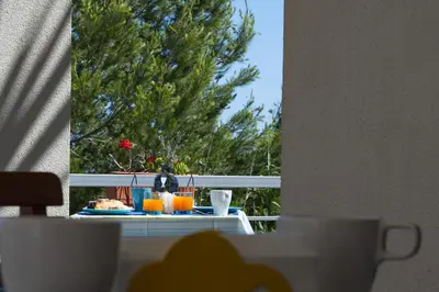 a table with food and drinks on a balcony with a tree at Casa Azul in Castellammare del Golfo