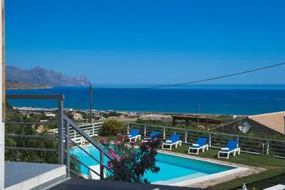 a view of a swimming pool with chairs and the ocean at Casa Azul in Castellammare del Golfo