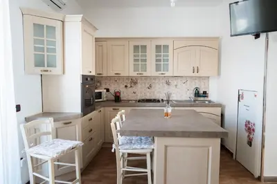 a kitchen with white cabinets and a kitchen island with stools at Locazione Turistica Aurora in Palermo