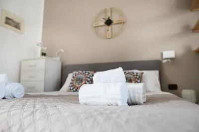 a bedroom with towels on a bed with a clock on the wall at Locazione Turistica Aurora in Palermo