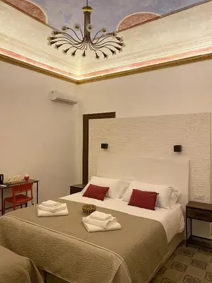 a bedroom with a large bed with a chandelier at Soste Normanne in Palermo