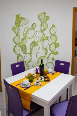 a white table with purple chairs and a yellow table cloth at My House Holiday Apartment in Palermo