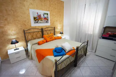 a bedroom with a bed with orange and blue pillows at My House Holiday Apartment in Palermo