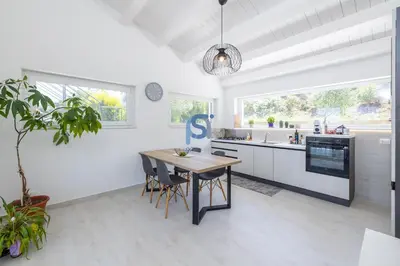 a white kitchen with a wooden table and a sink at Villa Irene Deluxe in Campofelice di Roccella