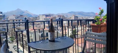 a table with two glasses and a bottle of wine on a balcony at Amedeo Suite - Palermo Centro in Palermo