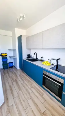 a kitchen with blue cabinets and a wooden floor at Villa Lilia - Private pool in Campofelice di Roccella