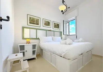 a white bedroom with a large bed and a table at Solemar Sicilia - Terrazza del Merlo in Palermo