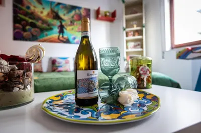 a bottle of wine sitting on a plate with a glass at Nanà Apartment in Palermo