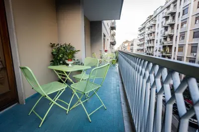 a balcony with green chairs and tables and buildings at Nanà Apartment in Palermo