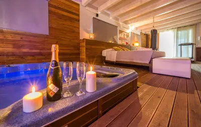 a room with a tub with a bottle of wine and candles at Oasi Relax - Romantic Room & Spa in Torretta