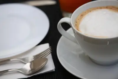 a cup of coffee on a table with a plate and spoon at B&B Massimo Inn in Palermo
