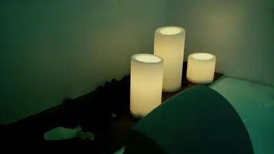 three white candles in a room with a green wall at B&B Massimo Inn in Palermo