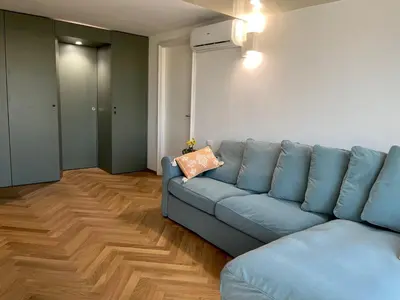 a living room with a blue couch and wooden floors at politeama view apartment in Palermo