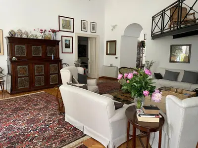 a living room with white furniture and pink flowers at Da Cristina Palazzo Atanasio in Palermo