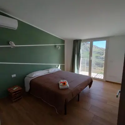 a bedroom with a large bed with a green wall at Villa Saint George in Scopello