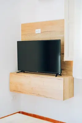 a flat screen tv on a wooden shelf on a wall at Giardino della Kalsa in Palermo
