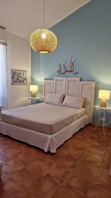 a large bed in a room with two tables and two lamps at Casa Corte Fiorita in San Vito lo Capo