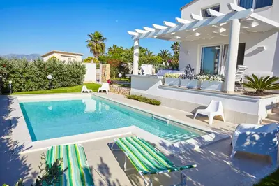 a swimming pool with two lounge chairs and a house at Villa Bianca in Alcamo