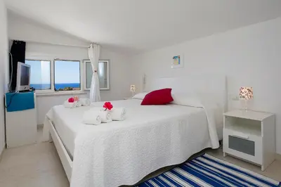 a white bedroom with a large white bed with red pillows at Villa Bianca in Alcamo