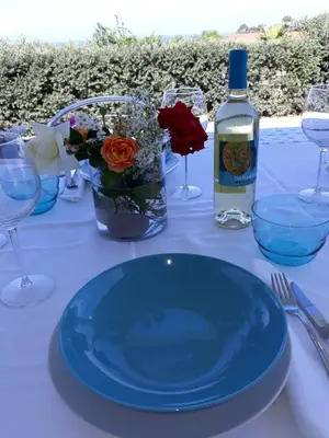 a table with a blue plate and a bottle of wine at Villa Bianca in Alcamo