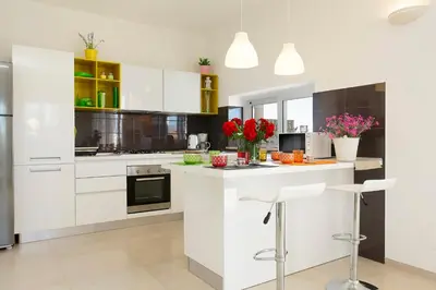 a kitchen with white cabinets and red flowers on the counter at Villa Bianca in Alcamo