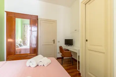 a bedroom with a bed and a desk with towels at Piazza Marina Holiday House by DomuSicily in Palermo