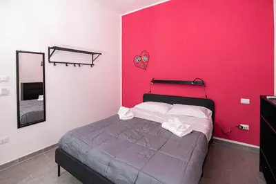 a bedroom with a bed with a pink wall at Splendori Rooms in Palermo