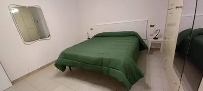 a bedroom with a green bed and a mirror at Casa Praiola in Terrasini