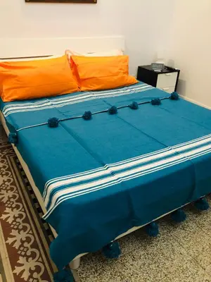 a blue bed with an orange pillow on it at B&B Giulio Cesare 24 in Palermo