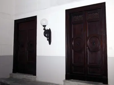 a pair of wooden doors with a light on a wall at B&B Giulio Cesare 24 in Palermo