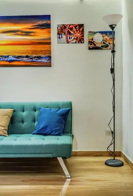 a green couch in a room with paintings on the wall at Sunflower Apartment in Palermo