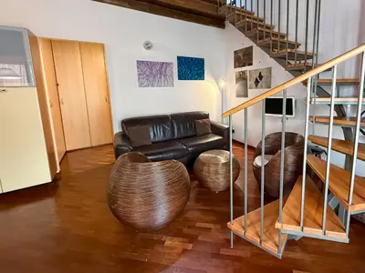 a living room with a leather couch and a staircase at Loft in Kalsa - By Rental BeB - in Palermo