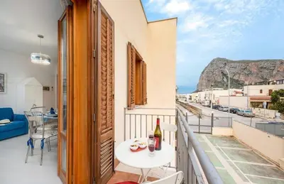 a balcony with a table and a bottle of wine at Residence Le Perle Beach in San Vito lo Capo