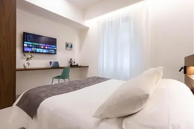 a bedroom with a white bed and a tv at Nora's Suites in Palermo