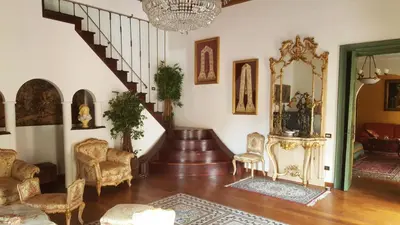 a living room with a staircase and chairs and a chandelier at Palazzo Viola Suite Panoramica Palermo in Palermo