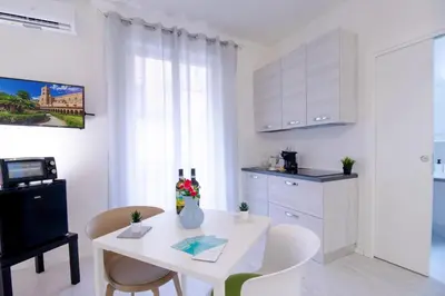a white kitchen with a white table and chairs at I tre Mori in Monreale