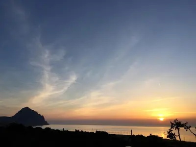 a sunset over the ocean with a mountain in the background at A Casa di Amy in Macari