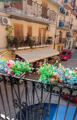 a table with flowers on a balcony of a building at Casa Sarina in Monreale