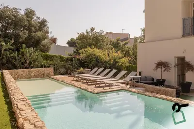 a swimming pool with lounge chairs next to a house at HOTIDAY Mondello Beach in Mondello