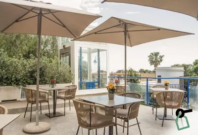 a patio with tables and chairs and umbrellas at HOTIDAY Mondello Beach in Mondello