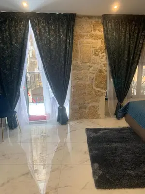 a bedroom with black curtains and a stone wall at Ai Chiavettieri Suite in Palermo